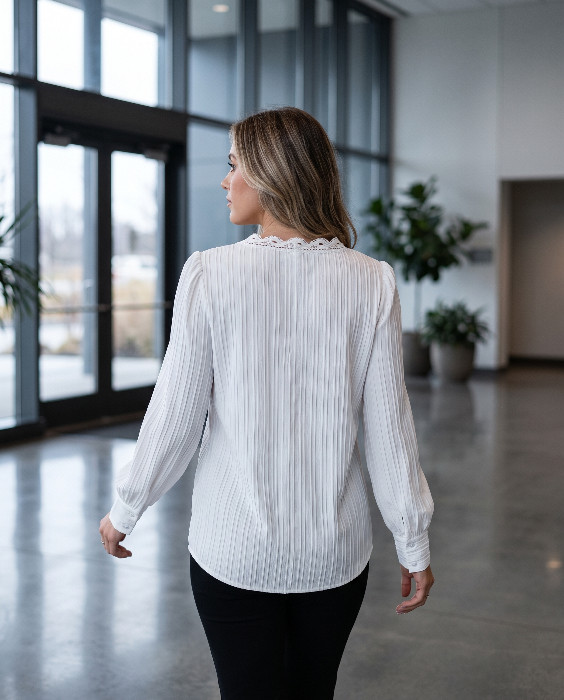 Woman walking through an office lobby in a tailored long sleeve pull-on blouse