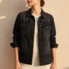 Black wash denim jacket worn buttoned against a warm plaster wall