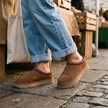 Brown suede slipper mules worn at an outdoor market