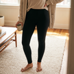 Solid black fleece lined leggings worn at home on a rug with a warm cardigan