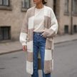 Checkerboard chunky knit cardigan worn open over jeans on a city street