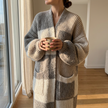 Checkerboard chunky knit cardigan wrapped closed by a sunlit window