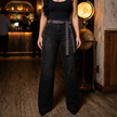 Black rhinestone flared jeans catching light in a warm evening interior