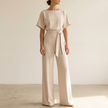 Beige belted wide leg jumpsuit against a warm off white wall