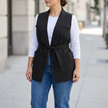 Black cargo pocket utility vest worn open over a white tee and denim