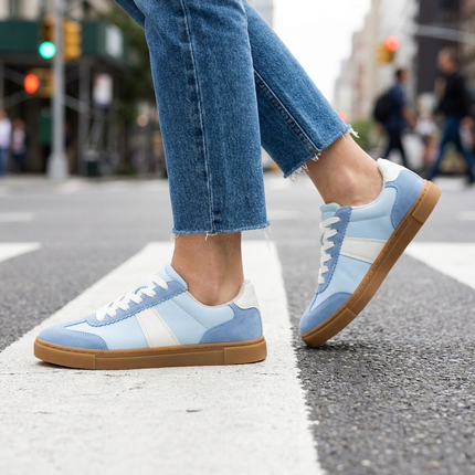 Womens suede sneakers mid stride on a city crosswalk