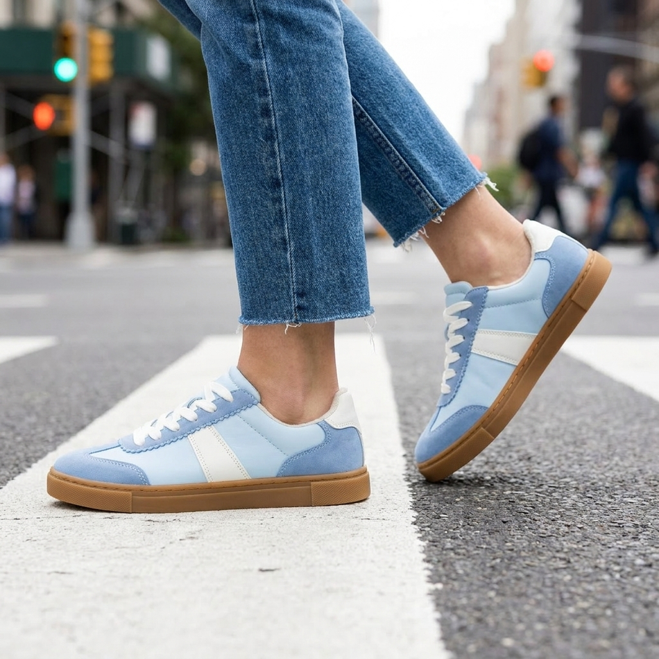 Womens suede sneakers mid stride on a city crosswalk