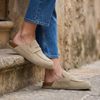Womens suede clogs resting on a stone step with cropped jeans