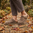 Womens buckle clogs walking a garden path scattered with leaves