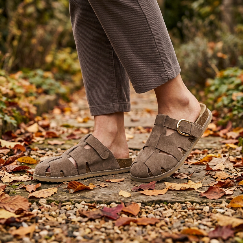 Womens buckle clogs walking a garden path scattered with leaves