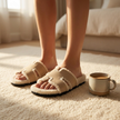 Womens shearling slippers on a cream rug beside a ceramic mug