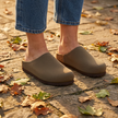 Womens knit clogs standing on a stone patio with autumn leaves