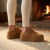 Suede platform clogs for women worn on a wool rug beside a fireplace