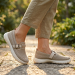 Womens buckle strap slip on sneakers stepping onto a stone garden path