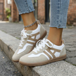 Womens retro sneakers with gum sole seated on a concrete step