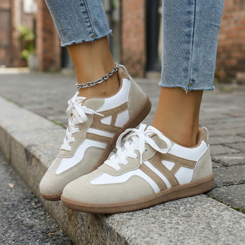 Womens retro sneakers with gum sole seated on a concrete step
