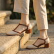 Womens square toe block heel T strap shoes resting on a stone step