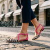 Strappy ballet flats for women, worn mid-stride crossing a sunlit city street