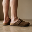 Leather clog mules for women, standing on a warm stone floor in soft daylight