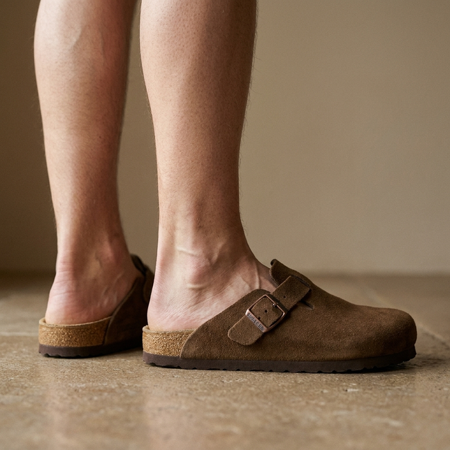 Leather clog mules for women, standing on a warm stone floor in soft daylight