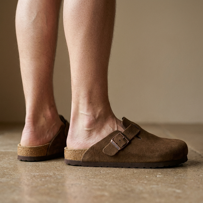 Leather clog mules for women, standing on a warm stone floor in soft daylight