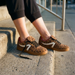 Retro low-top sneakers for women, worn sitting on sunlit concrete front steps