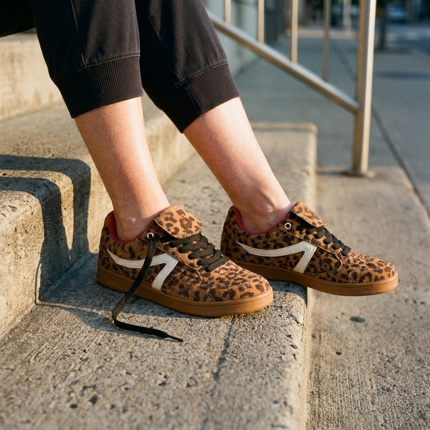 Retro low-top sneakers for women, worn sitting on sunlit concrete front steps