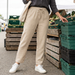Beige pull-on straight-leg trousers with white lace-up sneakers at an outdoor farmers market