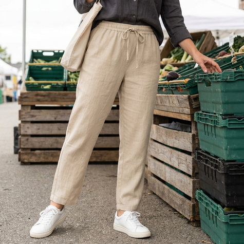 Beige pull-on straight-leg trousers with white lace-up sneakers at an outdoor farmers market