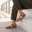 Tan lace up sneakers for women on a coastal boardwalk step