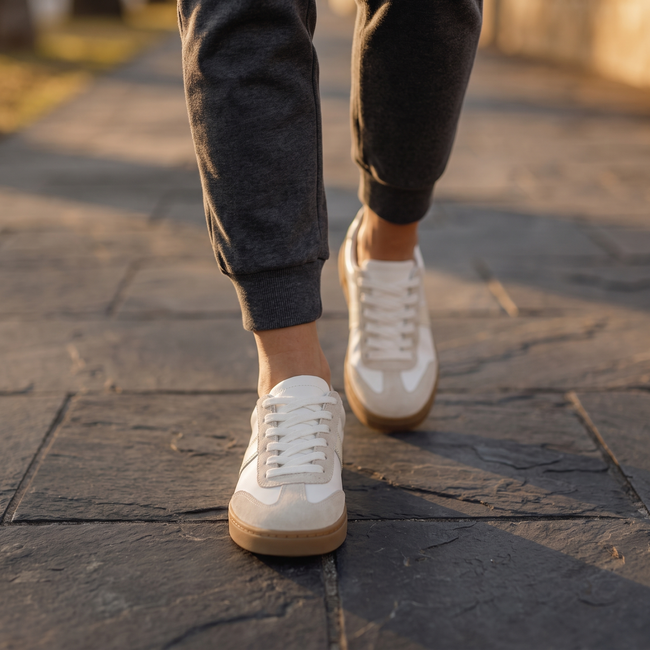 Ivory lace up sneakers for women walking on slate sidewalk at golden hour