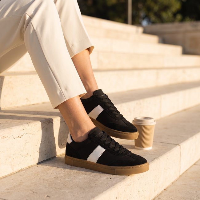 Black lace up sneakers for women seated on limestone steps