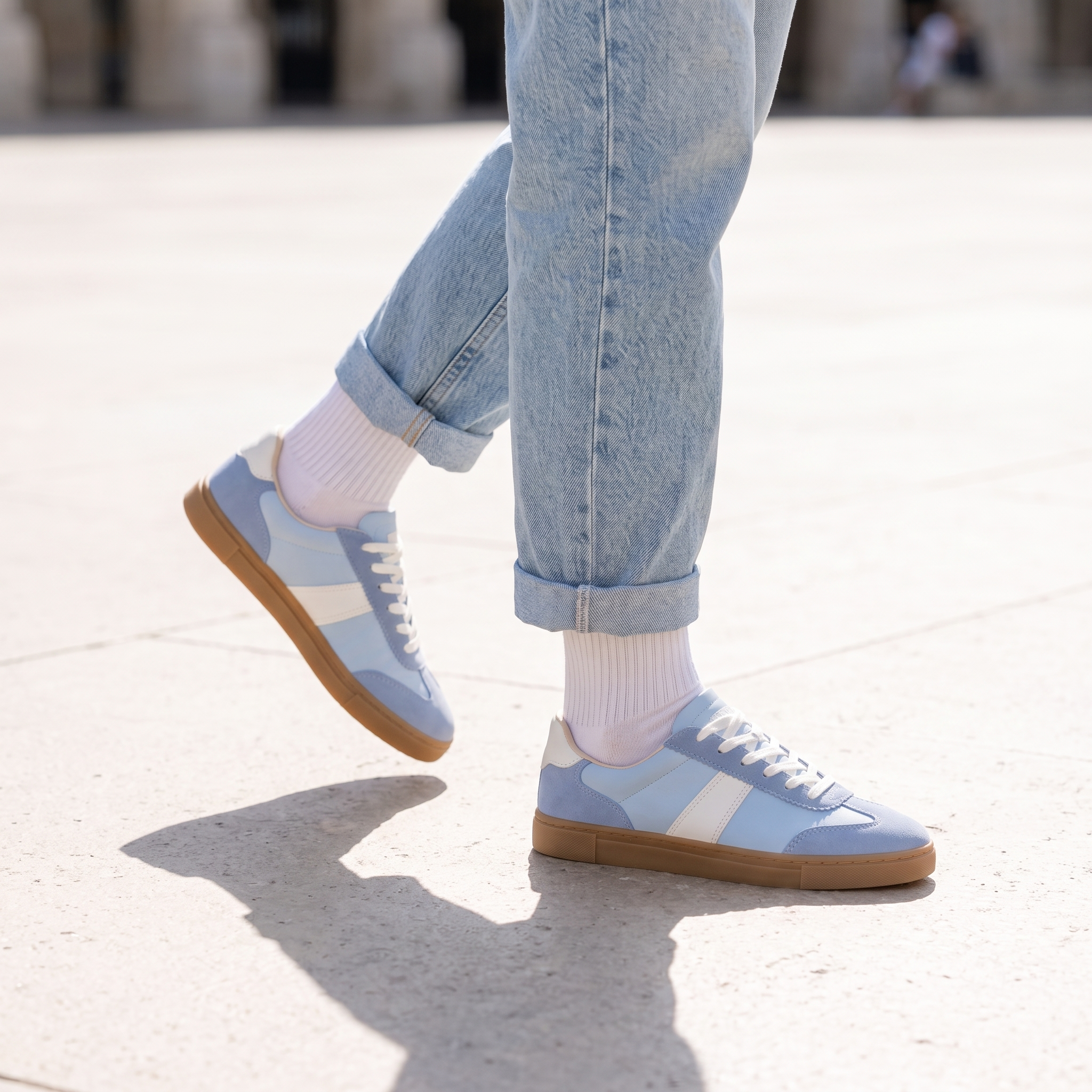 Blue lace up sneakers for women worn mid stride on a city plaza