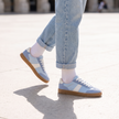 Blue lace up sneakers for women worn mid stride on a city plaza