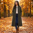 Woman wearing a green long button-front winter coat on an autumn park path