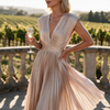 Womens wedding guest dress in champagne, pleated V neck maxi with cap sleeves, worn at a vineyard terrace