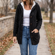 Women's hooded button front cardigan in black, worn open over a white tank