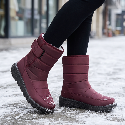 red waterproof snow boots for women on a snowy city sidewalk