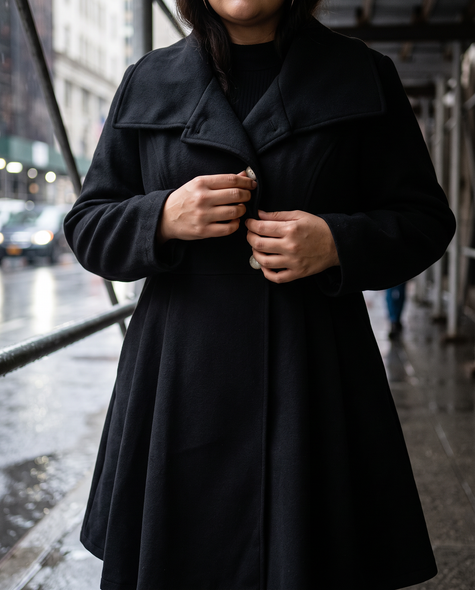 Buttoning an asymmetrical lapel collar coat on a rainy afternoon