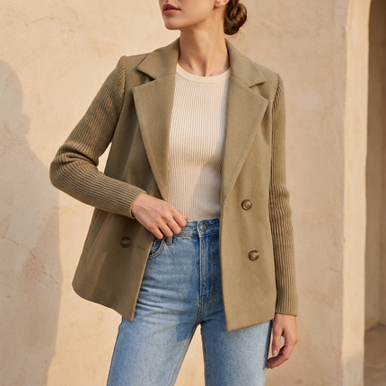 Khaki double breasted blazer worn open over denim against a warm wall